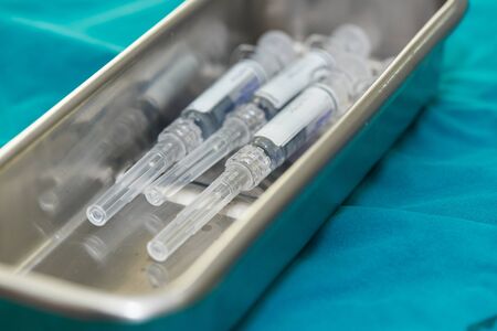 A group of syringes with needles for vaccination in stainless steel surgical tray on green table の写真素材