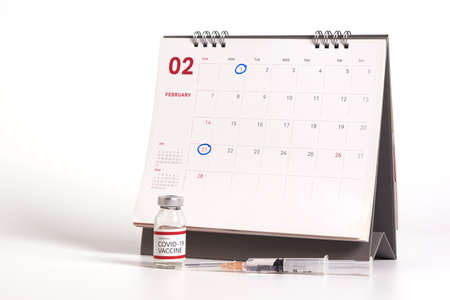 Concepts of coronavirus vaccine two doses injection. Injection at first week and third week for covid-19 antibody protection. Vaccine bottle, syringe, calendar on white backgroundの写真素材