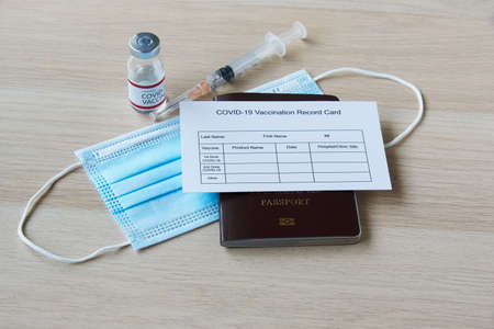 Travel in new normal. Passport, immunization record form, face mask , syringe and needle.の写真素材