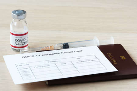 Passport and immunization record card for travel after vaccination.Syringe and  vaccine bottle.の写真素材