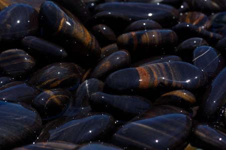 Close-up view of beautiful smooth black stones on the beach at koh hin ngam, Satun, Thailand.