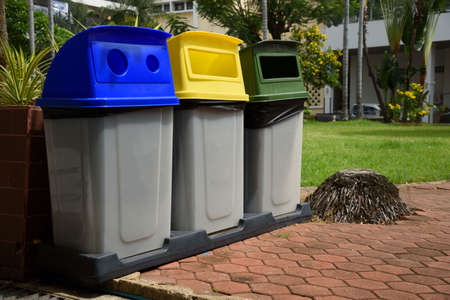 Garbage bins separated by colors foe recycling, glass and general waste placed outdoor.