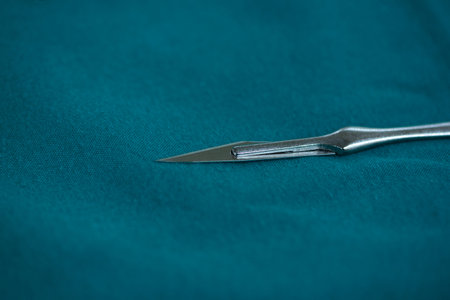 Close-up view of sterilized surgical blade number 11 on green table in operating room.の素材 [FY310208289152]