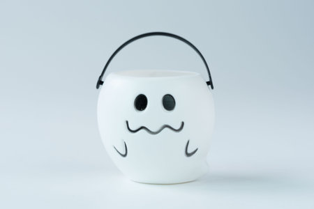 A charming white ghost-themed Halloween bucket with a smiling face and a black handle.の写真素材