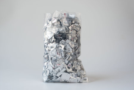 A clear plastic bag filled with empty aluminum blister pack scraps, highlighting pharmaceutical waste and environmental recycling concerns. The image emphasizes medical consumption, sustainability, and waste management.の写真素材
