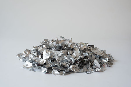 A large pile of empty aluminum medicine blister packs on a white surface, representing pharmaceutical waste, environmental issues, and the importance of recycling and proper disposal.の写真素材