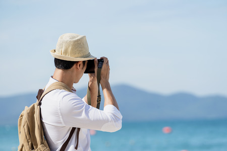 Young asian man take a photo pose. Man travel at sea and beach. Happy holidays concept.の写真素材