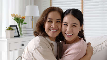 Attractive beautiful mum sit at cozy sofa couch living room in family moment grown up child kid look camera celebrate joy good warm time relationship with retired overjoy lady girl life insurance.の写真素材