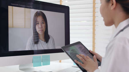 Attractive beautiful asia female doctor video conference call online live talk follow up remotely in...