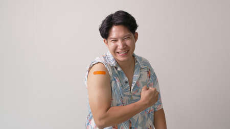 Adult mature attractive handsome asia hipster male after shot receive covid-19 anti virus vaccine in campaign vaccination safe life happy smile cheerful with bandage on arm with copy space.の写真素材