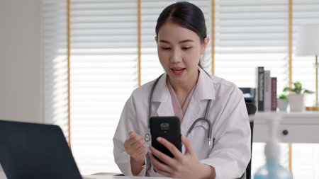 Attractive beautiful asia chinese female doctor video conference call online live talk follow up remotely in medical coronavirus result with patient at office. Online telehealth telemedicine service.の写真素材