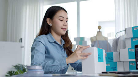 Young attractive beautiful hipster asia female packing product small business parcel order online retail store for delivery to customer. SME owner work preparing dropshipping box at home office.の写真素材