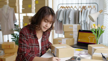 Young attractive beautiful hipster asia female packing product small business parcel order online retail store for delivery to customer. SME owner work preparing dropshipping box at home office.の写真素材