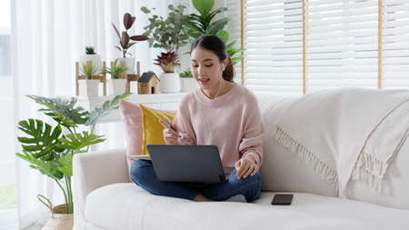 Young attractive business asian woman talking about sale report in video call conference on notebook computer online meeting in working from home, Working remotely and Social isolation concept.の写真素材