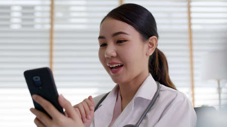 Attractive beautiful asia   female doctor video conference call online live talk follow up remotely in medical coronavirus result with patient at office. Online telehealth telemedicine service.の写真素材