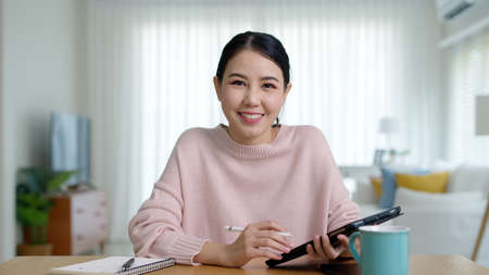 Portrait POV webcam camera computer screen of business female talking about sale report in video conference. Asian team using laptop and tablet online meeting in video call.Working from home remotely.の写真素材