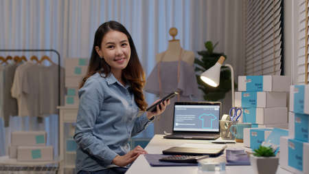 Portrait young attractive asia female owner startup business look at camera work happy with box at home prepare parcel delivery in sme supply chain, procurement, omnichannel commerce online concept.の写真素材