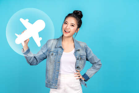 Young attractive beautiful asian woman holding white airplane paper smile positive ready for holiday travel reopen for leisure international travel in concept vaccine passport coronavirus health care.の写真素材