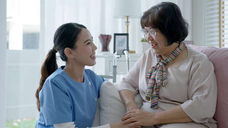 Young asian woman or nurse home care hand on senior grandmother shoulder give support empathy to elderly lady or older people in assisted living homecare mental health sick relief concept.の写真素材