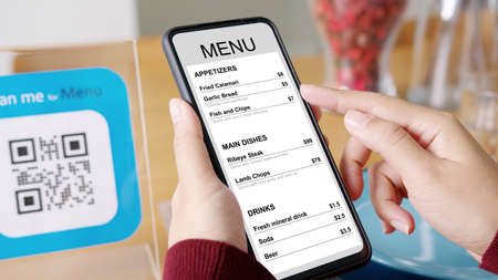 Hand's customer scan QR code for online menu service at table in restaurant during pandemic coronavirus. New normal contactless technology lifestyle protection coronavirus pandemic in restaurantの写真素材