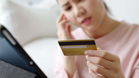 Upset young asia teen girl sit at home sofa couch feel shock broke doubt annoy or lost money in e-commerce app error buy issue, wrong hoax digital wallet hacked or bad theft steal crime fraud banking.の写真素材