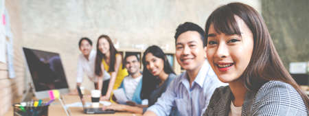 Banner of Happy creative team are smiling and looking at camera in modern workspace office. Happy group of confident employee in cowork. Relation and engagement concept.の写真素材