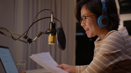 Asian female podcaster recording and broadcasting her podcast from home. Woman working from home at...