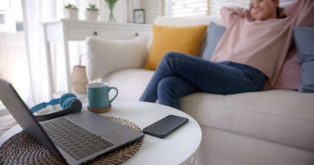 Asia lady people sitting easy hand behind head work at sofa cozy home lying down close cellphone...