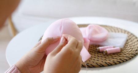 Close-up hand asia woman help make craft pink single fill up bra cup insert for post mastectomy...