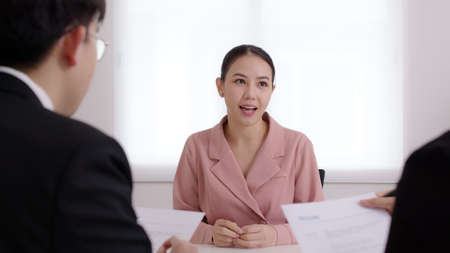 Asia young people jobless female or happy trainee student sit talk in company meeting with HR at office desk for employee new hire, review internship portfolio, customer positive feedback discussion.の写真素材