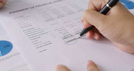Close-up people hand of female stock trader use pen write on tax plan paper check number data income ledger in balance sheet at office. Budget control in audit clerk work for loan risk MBA learning.の写真素材