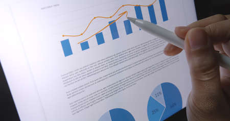 Close-up hand use pen write check growth data number on touch screen laptop note pad app. Loan agent...