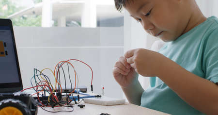 Asia home school young small kid happy smile self study online lesson excited make AI circuit toy. STEM STEAM digital scratch class on laptop screen for active children play arduino enjoy fun hobby.の写真素材