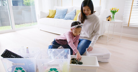 Mom teach Gen Z preteen girl kid dump paper glass can e-waste bag in reuse bin recycle bank help climate change social issue in asia people. Trash sorting clean eco green zero waste fun learn at home.の写真素材