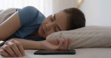 Asia teen woman wear smartwatch for sugar tracker, blood pressure tracking, resting sleep rate on arm IoT tech collect data app device relax body on cozy bed in future life at home.の写真素材