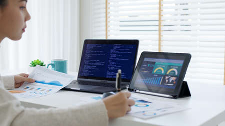 Back rear view of young asian woman, freelance data scientist work remotely at home coding...