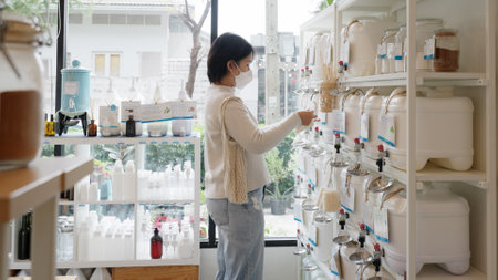 Asia vegan young adult woman carry bag happy buy eco bio goods glass jar pack on shelf. Trendy life SME startup store go green market refill bulk shop reduce climate change net zero free concept.の写真素材