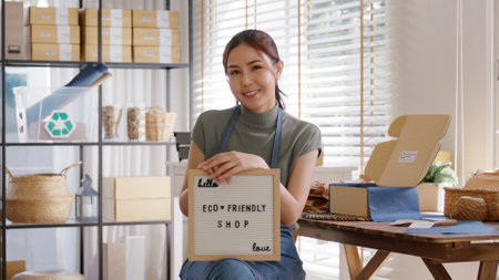 Go green vendor use eco care packaging box in net zero waste store asian seller retail home office shop. Small SME owner young adult woman asia Gen Z people happy relax smile pride looking at camera.の写真素材