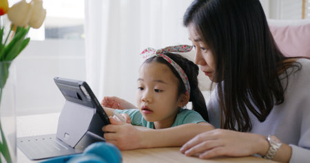 Cute asia people alpha small Gen Z kid fun talk play learn on smart tablet app game with mum at home sofa. Enjoy Child care little girl and mom happy smile relax teach study upskill idea online class.の写真素材