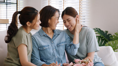Happy time May Mother day cuddle hug care love face to face kiss cheek to mature mum. Asia middle aged old mom adult people smile enjoy receive gift flower from young child sitting at home sofa relax.の写真素材