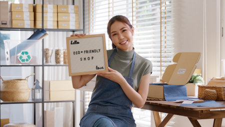 Go green vendor use eco care packaging box in net zero waste store asian seller retail home office shop. Small SME owner young adult woman asia Gen Z people happy relax smile pride looking at camera.の写真素材