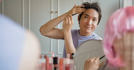 Gay queer man non-binary beauty blogger makeup artist at home cross dressing up apply face skin care eye make up brush. Real asia LGBT young guy adult people happy relax smile looking at mirror pride.の写真素材