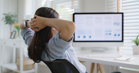 Asia people workforce young woman remote work at home office sit easy relax enjoy break time life balance put hands behind head and lean back on cozy desk. Teen girl stress relief look at desktop PC.の写真素材