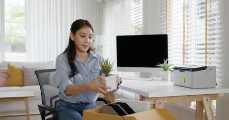 Future of workforce remote work fully permanent. Asia people happy relax move job to new small workspace set up desk picking file folder from box. Keep it chores neat start long term plan career work.の写真素材