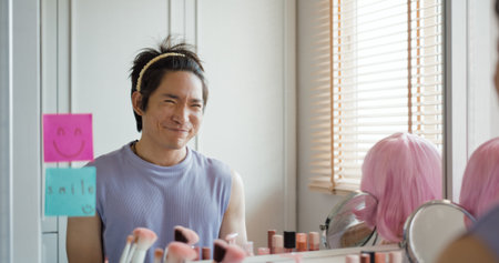 Gay queer man non-binary beauty blogger makeup artist at home cross dressing up apply face skin care eye make up brush. Real asia LGBT young guy adult people happy relax smile looking at mirror pride.の写真素材