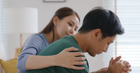Asia young people stress relief trust talk share suffer cancer pain sick family loss bad news crisis. Sorrow cry man and carer woman sit at sofa home help listen by love hold hand warm hug touch wife.の写真素材