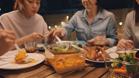 Enjoy eat yummy thai food with rice curry and drink at dine table outdoor house night party with mum. Asia older people mom and young adult child smile relax meet happy picnic meal warm time talk fun.の写真素材