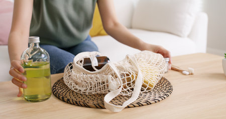 Young Gen Z girl asia people sit at home sofa couch unpack reuse mesh bag buy from eco friendly...