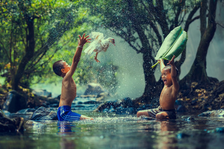 Couple children playing catch duck in riverの写真素材