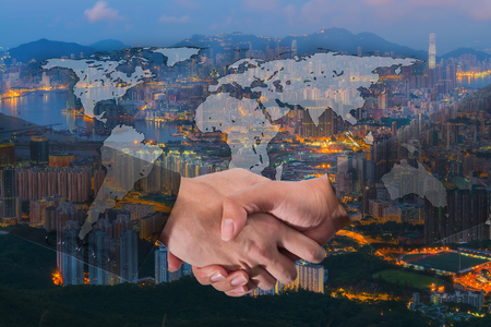 Double Exposure of a businessman handshake on World Global Cartography Globalization with Cityscape Hong Kong Panoramic Night Conceptの写真素材